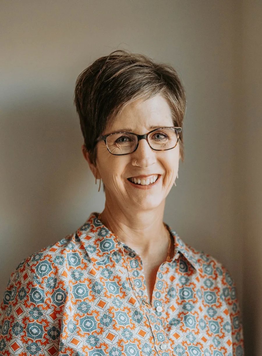 Kelly Wood, LCSW, smiling, wearing glasses and a patterned blouse.